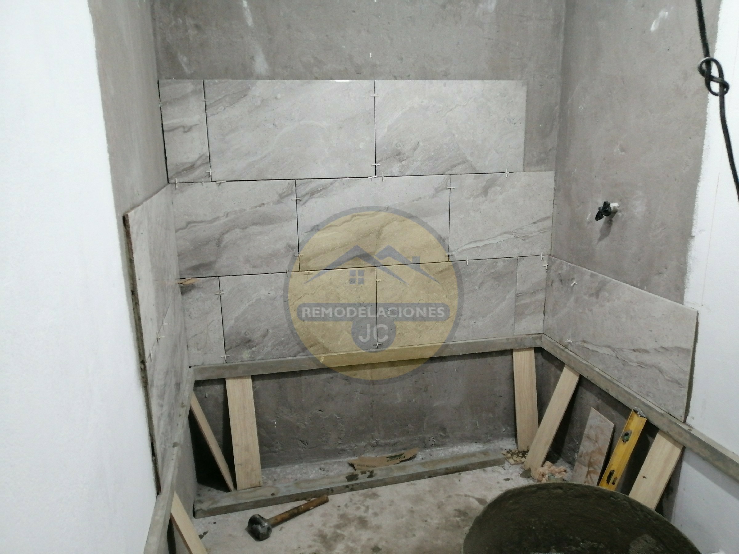 pegar baldosas en pared de ducha en baño de casa